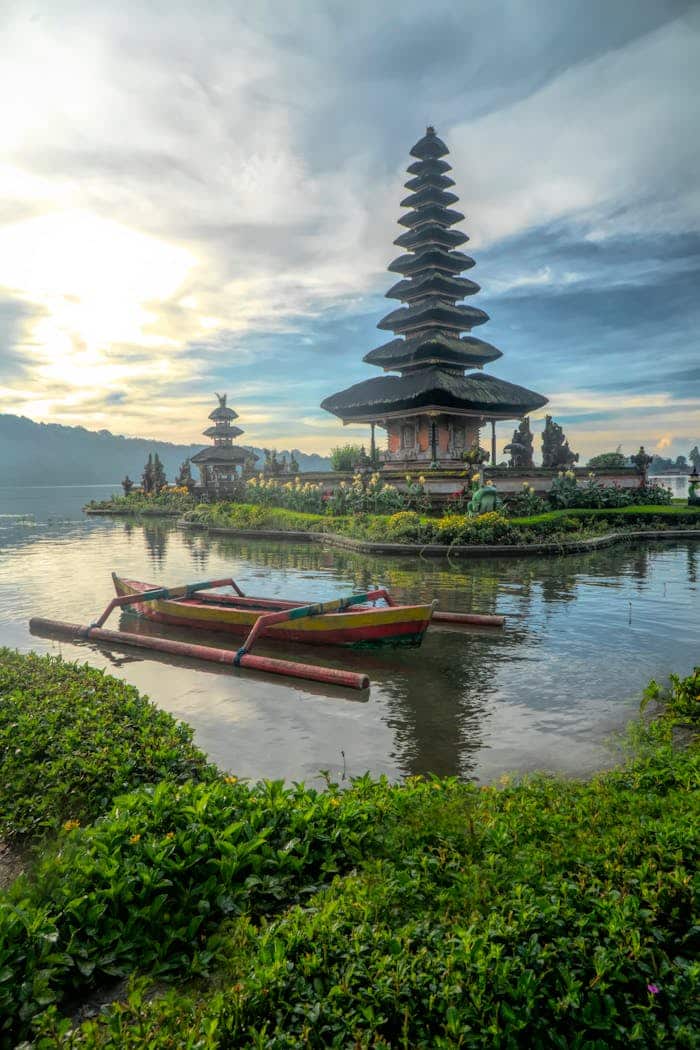 about-img Scenic view of Ulun Danu Beratan Temple with boats on Bratan Lake, Bali at dawn.